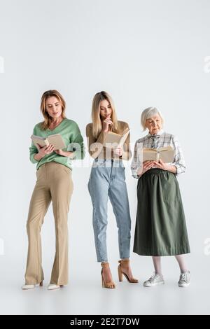 Die ganze Länge von drei Generationen von Frauen, die Bücher lesen Weiß Stockfoto