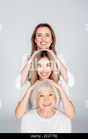 Drei Generationen von glücklichen Frauen isoliert auf grau Stockfoto