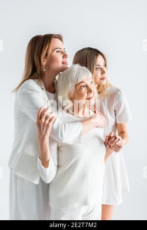 Drei Generationen von Frauen zufrieden lächeln, während sie sich isoliert umarmen Weiß Stockfoto