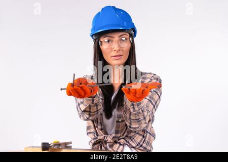 Niedliche Frauen in einem Helm und Brille posiert mit Nägeln in den Händen auf einem weißen Hintergrund. Stockfoto