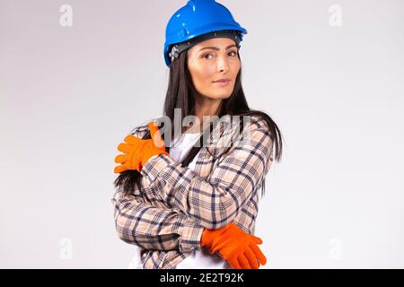 Junge Mechanikerin in Hut und schützende Bauhandschuh posiert auf grauem Hintergrund. Gleichstellung der Geschlechter, furchtlos, stark . Stockfoto
