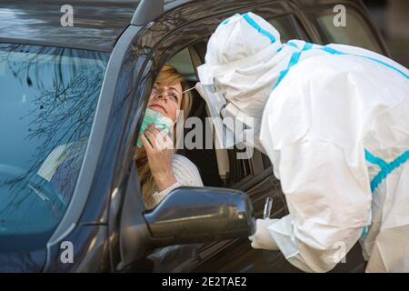 Medizinisches Personal Durchführen Drive-Thru COVID-19 Test, unter nasalen Tupfer Probe von weiblichen Patienten durch Auto-Fenster, PCR-Diagnose für Coronavirus, d Stockfoto