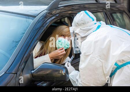 Medizinisches Personal Durchführen Drive-Thru COVID-19 Test, unter nasalen Tupfer Probe von weiblichen Patienten durch Auto-Fenster, PCR-Diagnose für Coronavirus, d Stockfoto