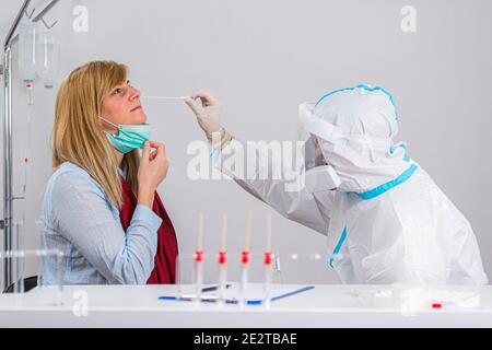 Medizinisches Personal, das COVID-19 Test durchführt, nasale Abstrichprobe von weiblicher Patientin im Krankenhauslabor nimmt, PCR-Diagnostik für Coronavirus, Arzt in PPE U Stockfoto