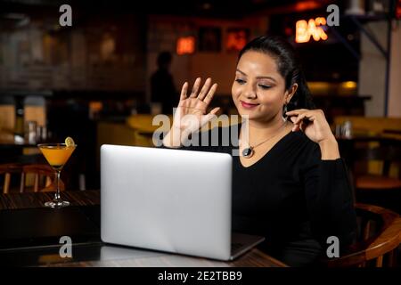 Porträt einer Geschäftsfrau, die in einem Restaurant an einem Laptop arbeitet, Konzept für soziale Medien, Videokonferenzen. Stockfoto