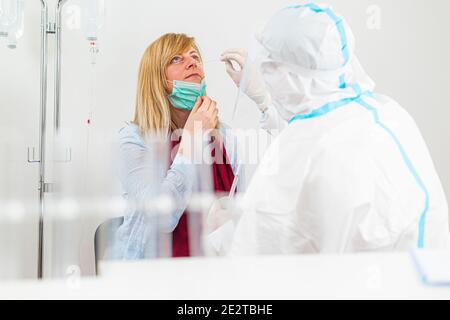 Medizinisches Personal, das COVID-19 Test durchführt, nasale Abstrichprobe von weiblicher Patientin im Krankenhauslabor nimmt, PCR-Diagnostik für Coronavirus, Arzt in PPE U Stockfoto