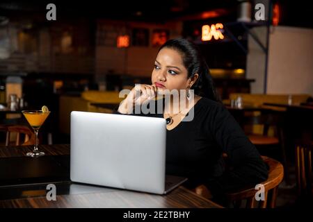 Porträt einer Geschäftsfrau, die in einem Restaurant an einem Laptop arbeitet, Konzept für soziale Medien, Videokonferenzen. Stockfoto