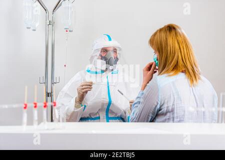 Medizinisches Personal, das COVID-19 Test durchführt, nasale Abstrichprobe von weiblicher Patientin im Krankenhauslabor nimmt, PCR-Diagnostik für Coronavirus, Arzt in PPE U Stockfoto