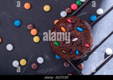 Schokoladenmuffin mit bunten Süßigkeiten bestreut. Bonbons in farbiger Glasur. Stockfoto