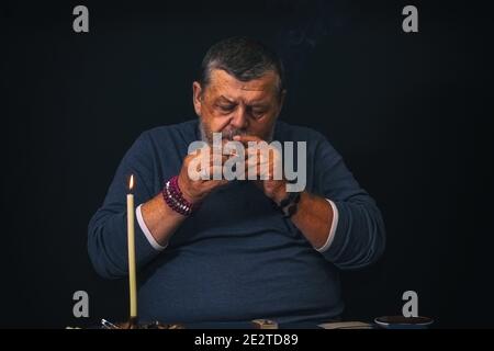Schönes, dezernes Porträt eines älteren Mannes - Beleuchtung für Rutscher Eine Zigarre hoch Stockfoto
