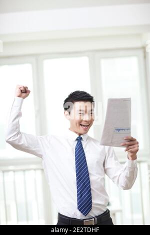 Portrait des jungen Geschäftsmannes stehend, Dokumente suchen und halten Liste auf Hochwertige Fotos Stockfoto