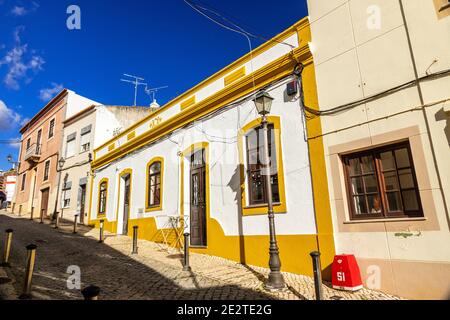 Historische Häuser mit altem Kulturerbe Hell bemalt im Stadtzentrum von Silves an EINER gepflasterten Straße (portugiesische Calçada), Silves an der Algarve Portugal Stockfoto