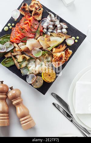 Seafood-Platte. Verschiedene leckere Meeresfrüchte mit Gemüse. Weißer Hintergrund. Stockfoto