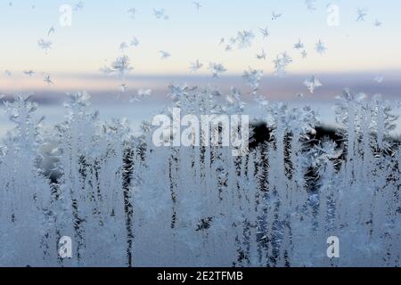 Frostmuster am Fenster mit Blick auf den Sonnenuntergang im Freien hinter Kristalle Stockfoto