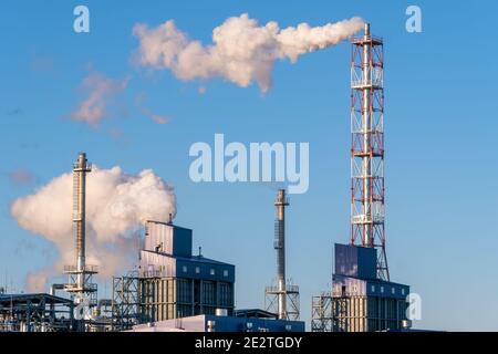 Rohre mit riesigen Rauchwolken in der Fabrik Nahaufnahme gegen den blauen Himmel an einem sonnigen Tag. Konzept der Ökologie, Umweltverschmutzung Stockfoto