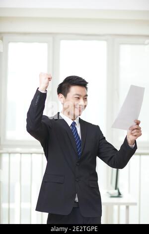 Portrait des jungen Geschäftsmannes stehend, Dokumente suchen und halten Liste auf Hochwertige Fotos Stockfoto