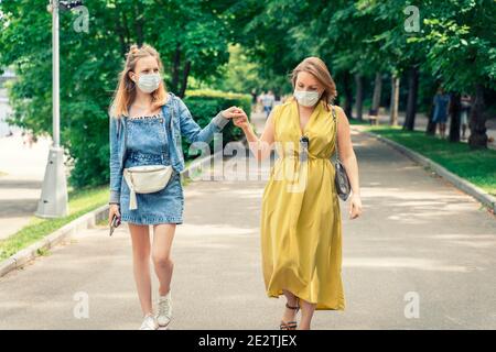 Mama und teen Tochter verbringen Zeit zusammen im Park. Menschen auf einem Spaziergang in Einweg-Masken. Stockfoto