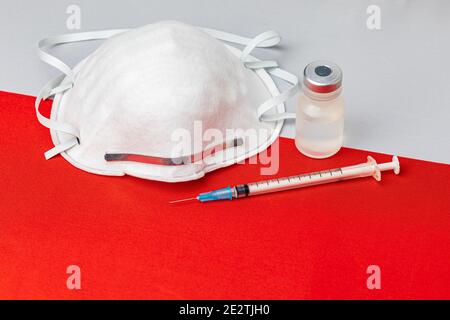 Polen Flagge, N95 Gesichtsmaske, Nadelspritze und Fläschchen. Konzept der Covid-19 Coronavirus-Impfstoffverteilung, Versorgungsengpässe und Gesundheitskrise Stockfoto