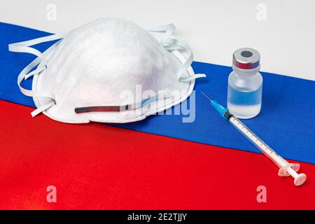 Russland Flagge, N95 Gesichtsmaske, Nadelspritze und Fläschchen. Konzept der Covid-19 Coronavirus-Impfstoffverteilung, Versorgungsengpässe und Gesundheitskrise Stockfoto