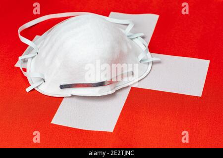 Schweiz Flagge und N95 Gesichtsmaske. Konzept der Covid-19 Coronavirus-Sperre, Reiseverbot und Gesundheitskrise Stockfoto