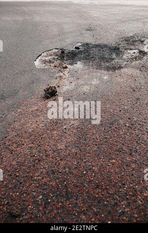 Tiefes Loch im Asphalt auf der Straße - beschädigt Straßenbelag - kalte Jahreszeit Stockfoto
