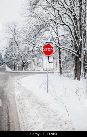 HALTEN Sie DAS Straßenschild an der Kreuzung mit einer Hauptstraße - Verkehrssicherheit im Winter Stockfoto