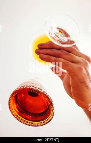 Männliche Hand mit einem Glas Brandy in der Nähe der Flasche - Ansicht von unten Stockfoto