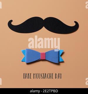 Nahaufnahme eines Schnurrbartes, hergestellt mit einem Ausschnitt aus einem schwarzen Karton, einer Fliege und dem Text gefälschter Schnurrbart Tag auf braunem Hintergrund, im quadratischen Format Stockfoto