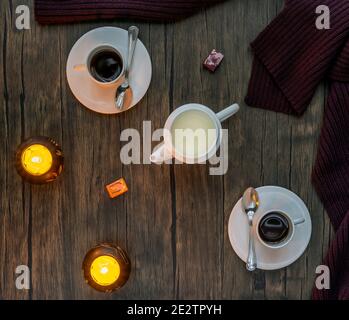 Draufsicht auf einen Espresso-Kaffee für zwei Personen mit Weiße Tassen und Milchkännchen mit gelben Kerzen auf Holz Hintergrund Stockfoto