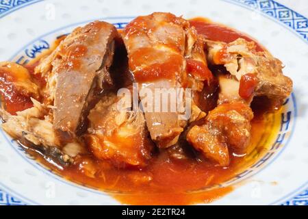 Makrele aus der Dose in Tomatensauce auf einem Porzellanteller Stockfoto