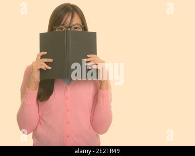 Jungen asiatischen Jugendmädchen versteckt sich hinter Buch Stockfoto