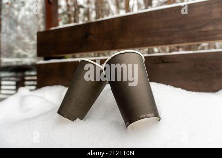 Zwei Pappbecher mit Kaffee auf einer Schneebank küssen Einander im Winter Stockfoto