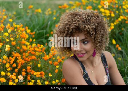 Porträt einer schönen Frau in einem Blumenfeld mit Kurze blonde lockiges Haar Stockfoto