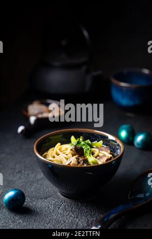 Asiatische Ramen Nudeln Suppe mit Rindfleisch, Austernpilzen und Gemüse in Schüssel auf dunklem Hintergrund Stockfoto