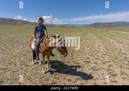 Tolbo, Mongolei - 4. August 2019: Junge zu Pferd auf der Steppe in der Mongolei. Stockfoto