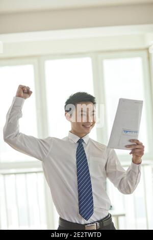Portrait des jungen Geschäftsmannes stehend, Dokumente suchen und halten Liste auf Hochwertige Fotos Stockfoto