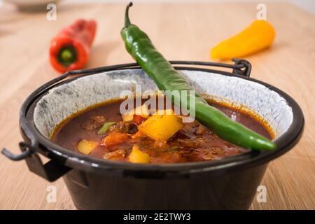 Ungarische Rindergulasch oder Gulyas Suppe oder Eintopf serviert in einem kleinen Kessel mit Kartoffeln, Fleisch, Paprika und Chili und Paprika Stockfoto