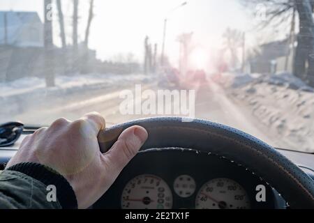 Hand eines Mannes auf dem Lenkrad eines Auto, das auf einer rutschigen Straße fährt Stockfoto