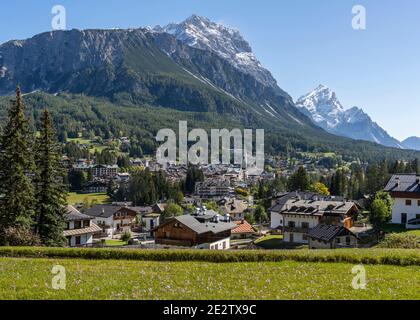 Cortina d'Ampezzo, Italien - 8. Oktober 2020: Die Stadt Cortina d'Ampezoo mit hohen schneebedeckten Bergen und Blumen, Herbst Krokus, im Vordergrund. Stockfoto