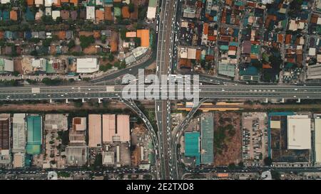 Von oben nach unten fahren Autos an der Kreuzung Autobahn in Luftaufnahme. Autobahnverkehr in Manila Stadt auf Luzon Insel, Philippinen, Asien. Wundervolle Stadtlandschaft im Stadtzentrum Stockfoto