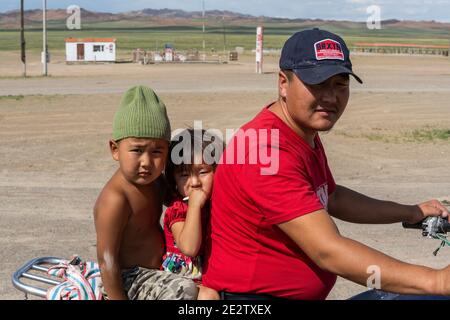 Olgii, Mongolei - 7. August 2019: Familie auf dem Motorrad mit zwei kleinen Kindern in der Steppe der Mongolei. Stockfoto