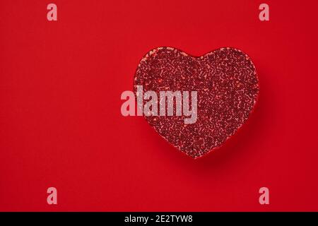 Schöne rote Herz-Box für ein luxuriöses Geschenk mit Perlen auf einem scharlachroten Hintergrund bestickt. Valentinstags-Postkarte. Draufsicht. Stockfoto