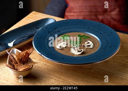 Köstliches Suppenpüree mit Wildpilzen auf Holztisch. Serviert in einem Restaurant, Menü. Stockfoto