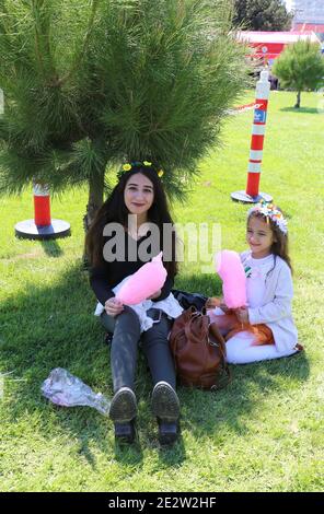 ADANA, TÜRKEI-9. APRIL: Unbekannte Schwestern sitzen auf Gras und genießen ihre Baumwolle Süßigkeiten am Orangenblütenkarneval.April 9,2017 in Adana, Türkei Stockfoto