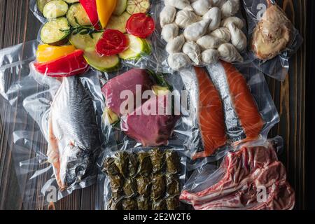 Produkte in Vakuumverpackung, auf einem Holzbrett. Gemüse, Fischfleisch, Dolma, Kurza. Quarantäne-Pandemie Stockfoto