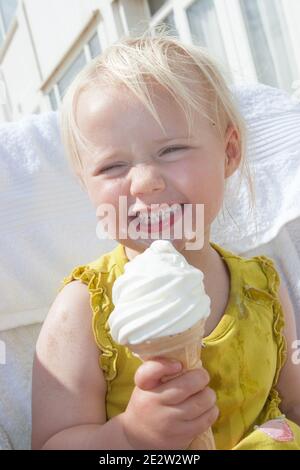 Ein junges blondes lächelndes Kleinkind Mädchen im Alter von 3 genießen ein Eis im Sommer am Meer in den Vereinigten Staaten Königreich Stockfoto