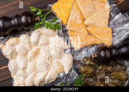 Produkte in Vakuumverpackung, auf einem Holzbrett. Gemüse, Fischfleisch, Dolma, Kurza. Quarantäne-Pandemie Stockfoto