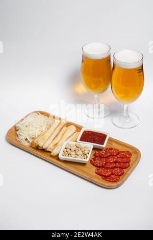 Frisches kaltes Bier und Snacks auf Tablett mit Käse und Wurst isoliert Stockfoto