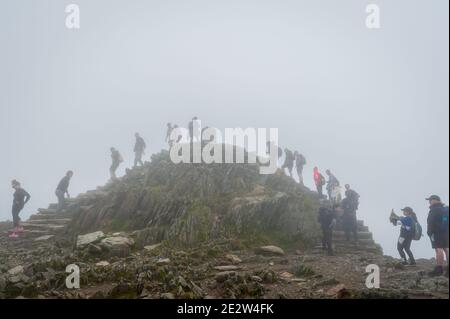 Snowdon, Großbritannien. 08/07/2020. Lockere Pandemiesperrregeln führten zu einer Zunahme von „tay-cations“. Touristen in der Warteschlange für ihre Reihe zu Peak für Selfie zugreifen. Stockfoto