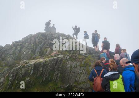 Snowdon, Großbritannien. 08/07/2020. Lockere Pandemiesperrregeln führten zu einer Zunahme von „tay-cations“. Touristen in der Warteschlange für ihre Reihe zu Peak für Selfie zugreifen. Stockfoto